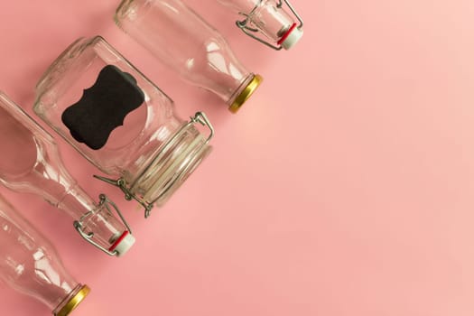 Glass bottles and jars on a pink background. Zero waste and ecological concept. Top view. Copy space.
