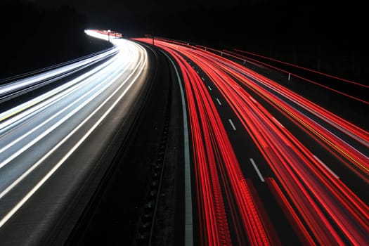 At night,Travel and good transport on the motorway - highway usually runs without traffic jams. Heatlights and taillights in red and white.