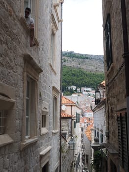 Dubrovnik, Croatia, 08.14. 2022. Narrow streets of the ancient town. The facades of the houses are made of marble and stone very close to each other. Windows with shutters. Summer tourism in Adriatic