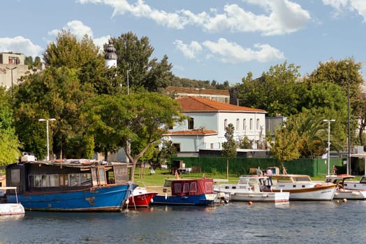 Istanbul, Turkey - September 1, 2022: Boats docked at the coast of the Golden Horn, with background of green park with dense big trees, and residential houses, in a sunny summer day