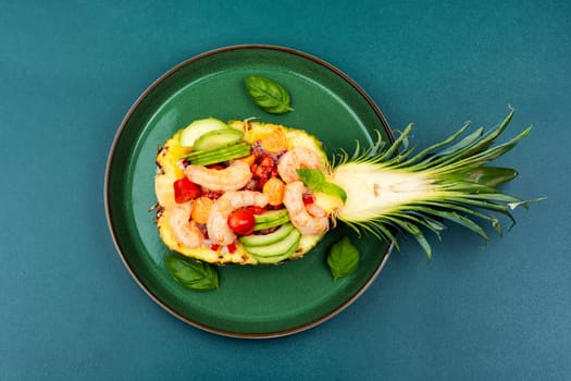 Half a pineapple with vegetables, rice and seafood on a white plate. Salad