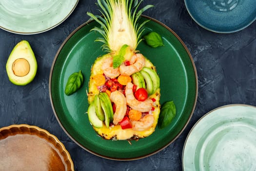 Half a pineapple with vegetables, rice and seafood on a white plate. Salad