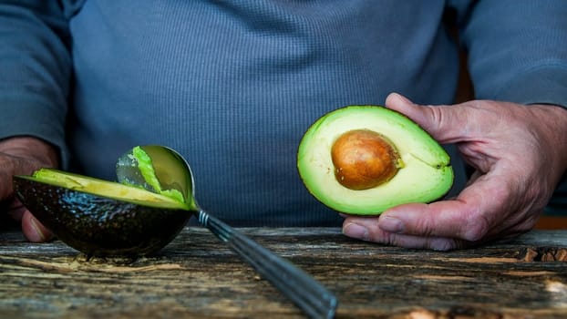 Man holding avocado in rustic wooden table  with copy space