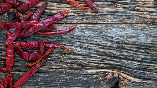 Dry sicy red pepper on rustic wooden background from above with copy space on bottom