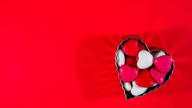 Heart shaped candy in form on red background with copy space