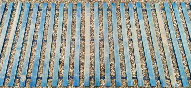 Wooden boardwalk on the beach. Sticks and boards on rocky ground. Heel protection from damage. Summer time and beach holidays. Travel and tourism concept.