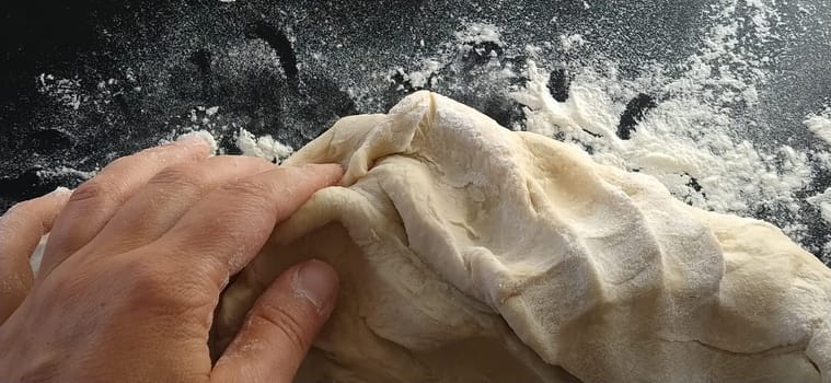 Hands knead the dough. The woman kneaded dough for baking or dumplings. Preparation of flour, water and egg mass for thermal processing. Chef hands.