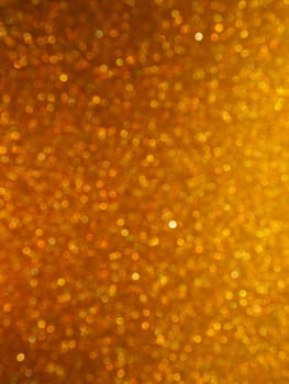 Bokeh light of gold glitters. Golden glitter texture background. Sparkling glitter wrapping paper with sequins and sparkles. Festive golden bokeh and glitter. Beautiful background
