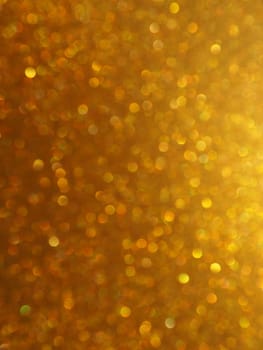 Bokeh light of gold glitters. Golden glitter texture background. Sparkling glitter wrapping paper with sequins and sparkles. Festive golden bokeh and glitter. Beautiful background