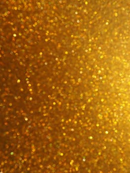 Bokeh light of gold glitters. Golden glitter texture background. Sparkling glitter wrapping paper with sequins and sparkles. Festive golden bokeh and glitter. Beautiful background