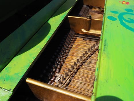 Strings, soundboard and piano mechanics. Piano on the street. Piano painted green. Performance of a piece of music. Street concert on a summer sunny day