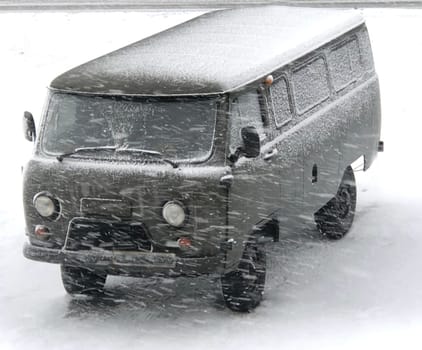 green military car in the snow in a blizzard