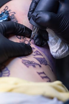 A woman getting a black script tattoo on her ribcage.