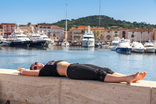 Girl and yachts on the coast of Saint Tropez, France. girl lying on the waterfront