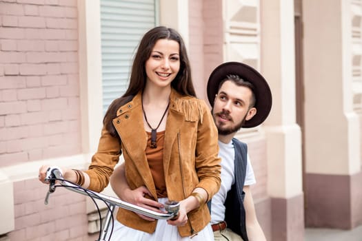 Young couple against the wall and hugging in city. girl sitting on a bicycle