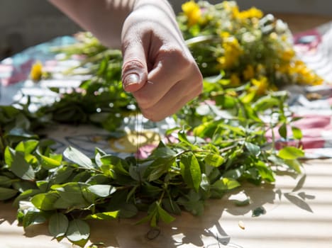 Woman Making a Swedish Midsummer Head Creation with flowers in the background.