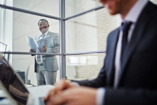 Confident businessman in suit looking at his working colleague
