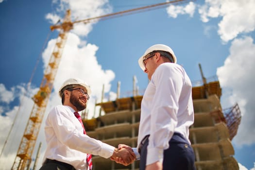 Two businessmen making agreement on background of new construction