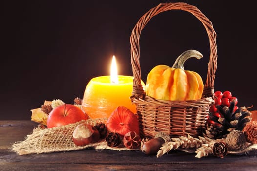 small pumpkin in a basket on old weathered wooden boards by candlelight