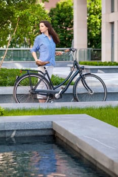 Pretty girl iin blue shirt with a bicycle at street