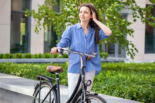 Pretty girl iin blue shirt with a bicycle at street
