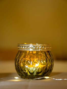 A lantern with a tea light atmospherically illuminates a table in the evening.