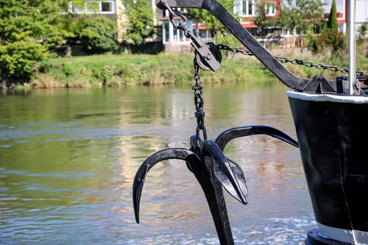 An anchor hangs from a chain on a barge.