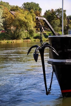 An anchor hangs from a chain on a barge.