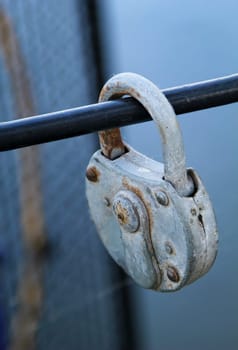 An old padlock, as a love lock, proof of love attached to a metal grille.