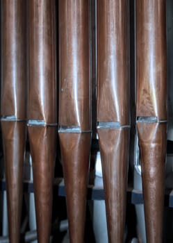 Many organ pipes stand side by side in an organ over a bellows.