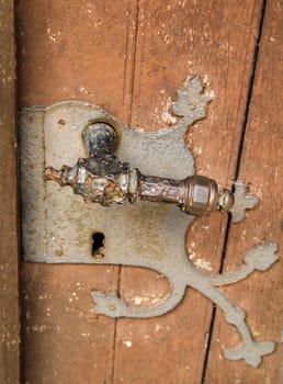 An old lock with an antique door handle. A wooden door with an old lock.