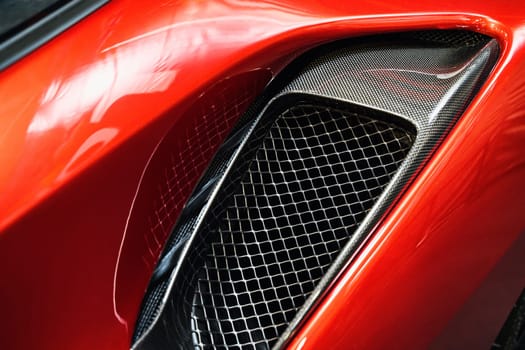 front view closeup detail of sport car with white metal hood and grey air flow intake ornament