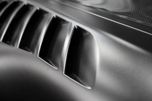 front view closeup detail of black sport car with dark metal hood and air flow intake ornament