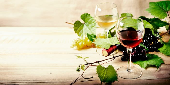Glass of red and white wine, bottle and grape vine on vintage wooden table. Winery and wine tasting concept. Restaurant vine list design banner background.