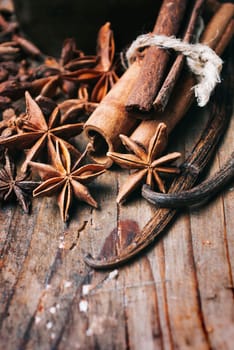 Closeup of anise seed, vanilla and cinnamon sticks on rustic wooden table. Holiday seasoning mix for cooking and baking dessert. Various aromatic spices flavor mixture on vintage background.