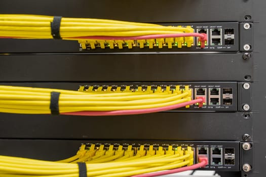 Selective focus on neat and tidy patched network cables, RJ45, connected to the switches and routers mounted on the rack in data centre, networking
