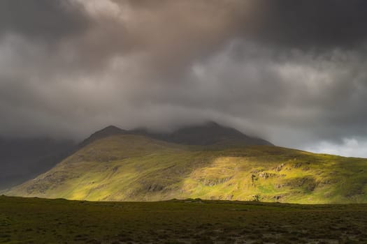 Doolough Valley, Glenummera and Glencullin mountain ranges illuminated by sunlight an partially covered by dark clouds, County Mayo, Ireland