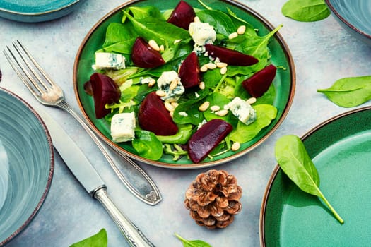 Salad with boiled beetroot, blue cheese, herbs and pine nuts. Food recipe background.