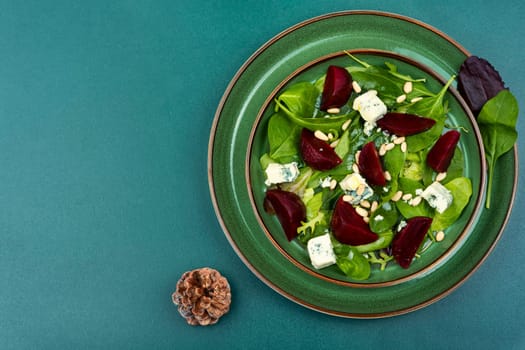Salad with boiled beetroot, blue cheese, herbs and pine nuts. Food recipe background.