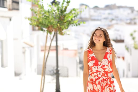 Front view portrait of a happy tourist walking and sightseeing in a white town