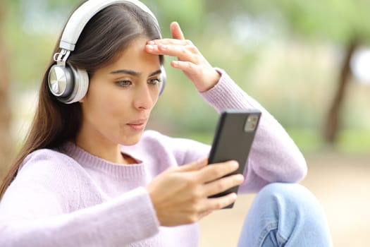 Woman surprised watching media on phone in a park