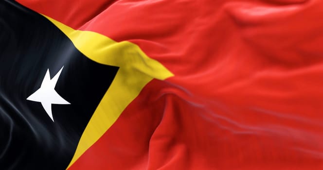 Detail of East Timor National flag waving. Red background with a yellow triangle and a black triangle with a white star. 3d illustration render. Selective focus. Close-up. Textured background