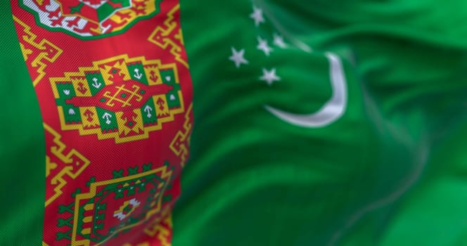 Detail of the Turkmenistan national flag waving. Green field, red vertical band, crescent moon, five stars, carpet motifs. 3d illustration render. Selective focus. Close-up. Textured background