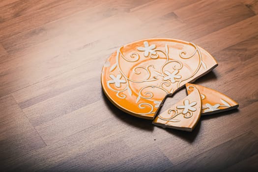 Broken ceramic plate on wooden floor
