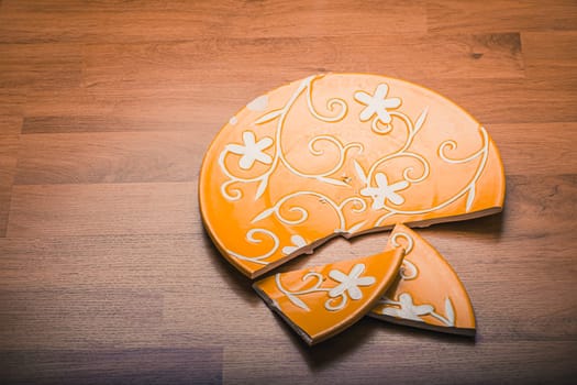 Broken ceramic plate on wooden floor