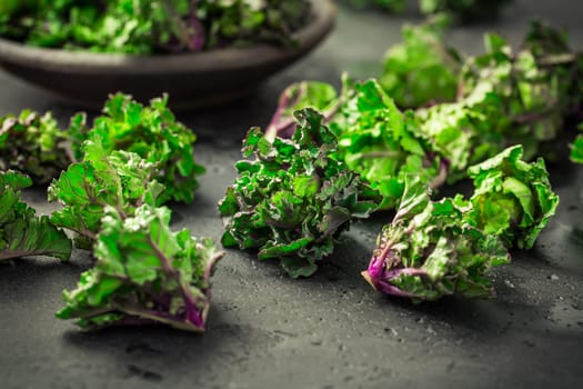 Kalette, kale sprouts, flower sprouts on black background. Hybrid plant, cross between kale and Brussels sprouts, heathy winter vegetable.