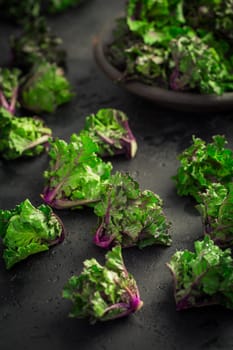 Kalette, kale sprouts, flower sprouts on black background. Hybrid plant, cross between kale and Brussels sprouts, heathy winter vegetable.