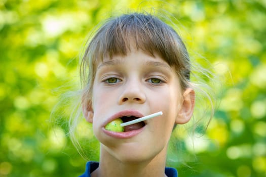 The girl has a big round lollipop in her mouth, close-up portrait