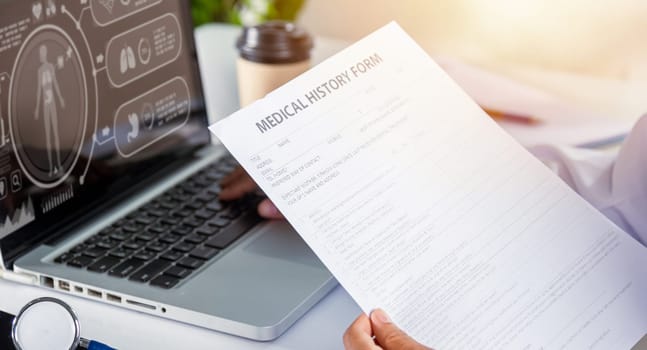 Doctor Day Concept. nurse woman in uniform with doctor stethoscope working typing information of patient prescription medical history form into laptop computer for record document data report
