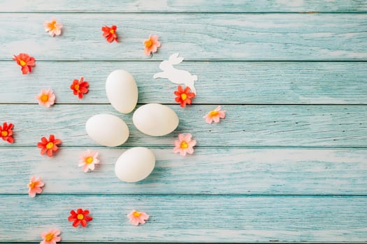 Happy Easter Day Concept. Top view of holiday banner background design white easter eggs and spring flowers on blue wooden background with empty copy space, celebration greeting card